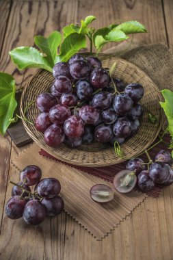 Hasır plaka ahşap masa üzerinde kırmızı üzüm demet.