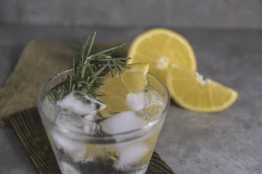 Tablo üzerinde alkollü içki cin tonik limon, biberiye ve buz ile görünümü Kapat.