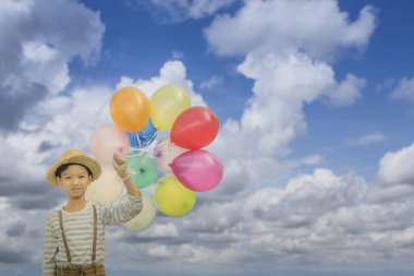 Grup mavi bulutlu gökyüzü arka plan üzerinde renkli balonlar ile mutlu Asyalı çocuk.