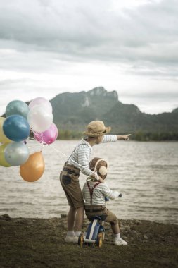 Sahilde küçük kardeşlerin balonlu arkadan görünüş.
