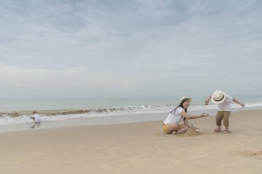 İki sevimli oğlu ile kumsalda oynarken annesi.