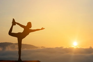 Pratik Yoga sahilde günbatımı zaman alacakaranlık gökyüzü arka plan ile kadın silüeti