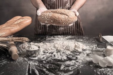 Adam ekmek, mutfak masasının üzerinde taze hamur üzerine un yağmurlama adam tabloda buns hazırlanıyor