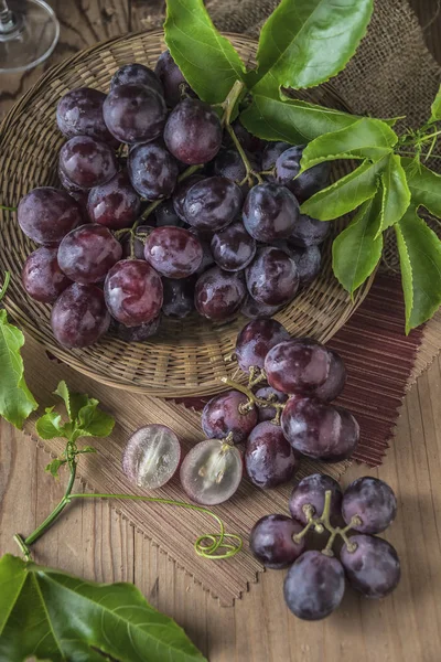 Ahşap masa yemeye hazır tabağa hasır sağlıklı kırmızı üzüm.