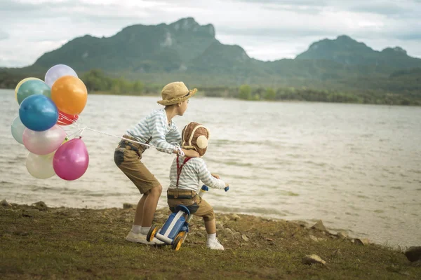 Mutlu çocuk ve kardeşi balonları, yaz büyük tatil zamanında sahip plaj renkli balonlar ile çalış. Yaşam tarzı, tatil, mutluluk, sevinç kavramı