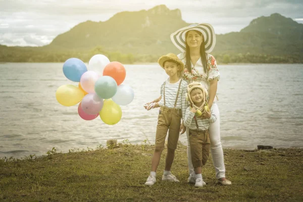 Asyalı kadın balonlar ile plajda durup oğulları sarılma.