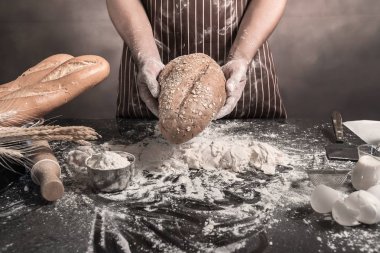 Adam ekmek, mutfak masasının üzerinde taze hamur üzerine un yağmurlama adam tabloda buns hazırlanıyor