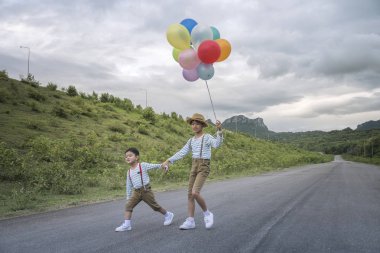 Yolda büyük tatil sahip renkli balonlar ile oynarken mutlu Asya çocuklar.