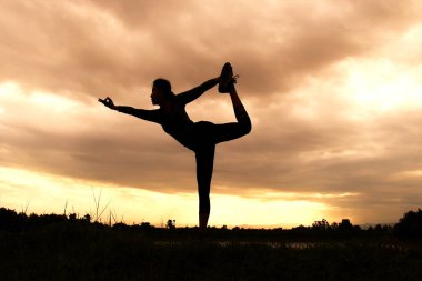 Kadın siluet pratik yoga sahilde günbatımı zaman alacakaranlık gökyüzü arka plan ile