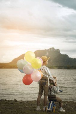 Sahilde küçük kardeşlerin balonlu arkadan görünüş.