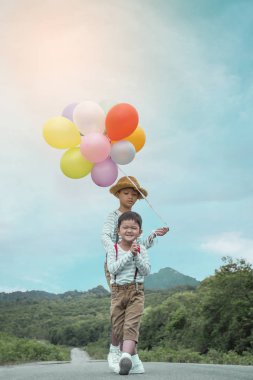 Mutlu çocuk ve kardeşi balonları, yaz büyük tatil zamanında sahip yolda renkli balonlar ile çalış. Yaşam tarzı, tatil, mutluluk, sevinç kavramı