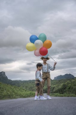 Yolda büyük tatil sahip renkli balonlar ile oynarken mutlu Asya çocuklar.