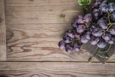 Ahşap masa üzerinde sağlıklı kırmızı üzüm demet.