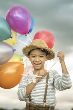 Asyalı çocuk renkli balonlarla kumsalda oynarken portresi.