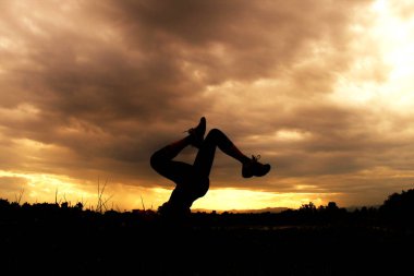 Pratik Yoga sahilde günbatımı zaman alacakaranlık gökyüzü arka plan ile kadın silüeti