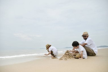 Mutlu bir aile babası ile iki oğlu sahil üzerinde oynama