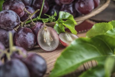 Hasır plaka ahşap masa üzerinde kırmızı üzüm demet.