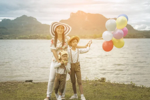 Happy family holding colorful balloons outdoor on the beach having great holidays time on summer. Lifestyle, vacation, happiness, joy concept