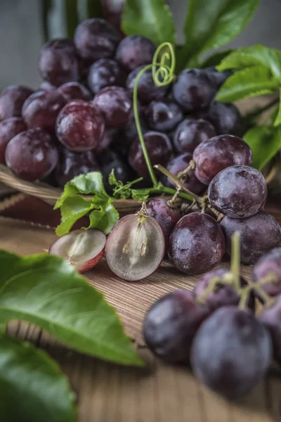 Ahşap masa yemeye hazır üzerinde hasır plaka sağlıklı kırmızı üzüm görünümü Kapat.