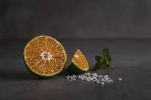 Fresh orange fruits with salt on stone table with copy space
