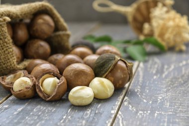 Macadamia fıstığı çuval ahşap zemin üzerine saçılan.
