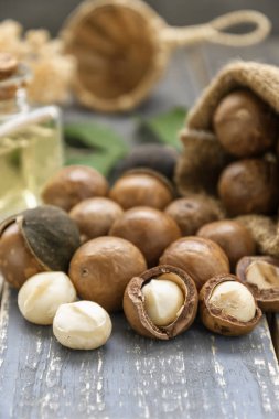 Macadamia fıstığı saçılan petrol şişe ahşap arka plan üzerinde olan torba.