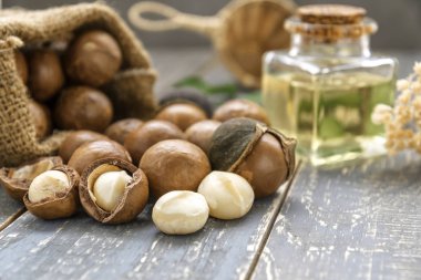 Macadamia fıstığı saçılan petrol şişe ahşap arka plan üzerinde olan torba.