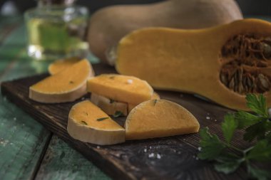 Butternut squashes dilimlenmiş eski ahşap arka plan, kabak parçaları, hasat üzerinde düşmek. Koyu kahverengi zemin. Sonbaharda yemek. Sağlıklı gıda.