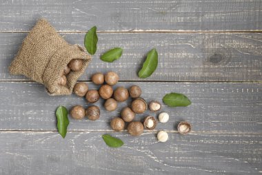 Macadamia fıstığı çuval ahşap zemin üzerine saçılan.