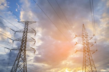 Yüksek gerilim kuleleri günbatımı gökyüzü arka plan ile.