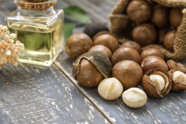 Macadamia fıstığı saçılan petrol şişe ahşap arka plan üzerinde olan torba.