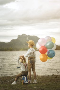 Balonlar ve renkli balonlarla kumsalda oynarken Bisiklet ile Asya kardeşler.