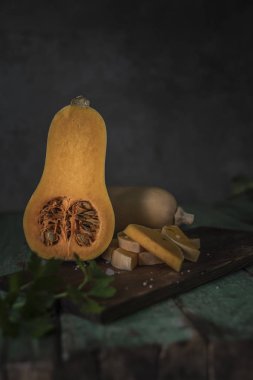 Butternut squashes dilimlenmiş eski ahşap arka plan, kabak parçaları, hasat üzerinde düşmek. Koyu kahverengi zemin. Sonbaharda yemek. Sağlıklı gıda.