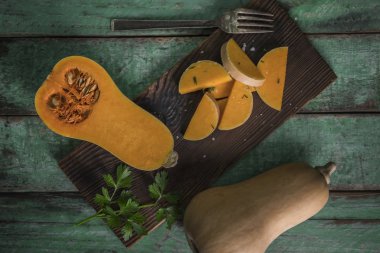 Butternut squashes dilimlenmiş eski ahşap arka plan, kabak parçaları, hasat üzerinde düşmek. Koyu kahverengi zemin. Sonbaharda yemek. Sağlıklı gıda.