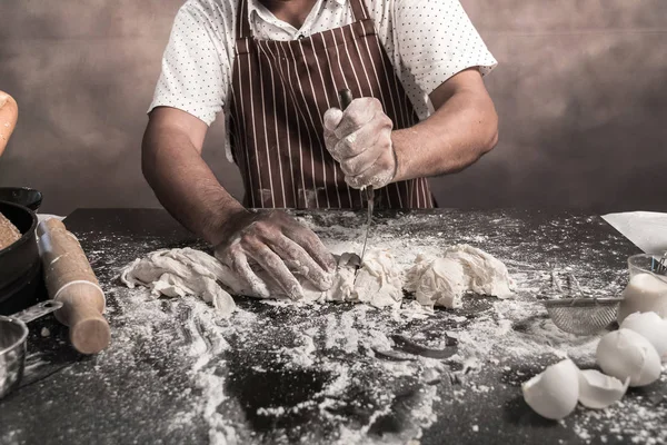 Man preparing buns at table in bakery.