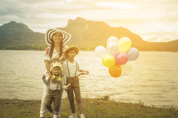 Happy family holding colorful balloons outdoor on the beach having great holidays time on summer. Lifestyle, vacation, happiness, joy concept