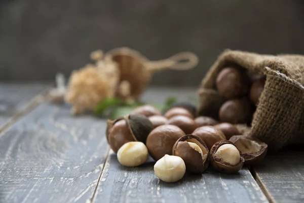 Nueces Macadamia Esparcidas Del Saco Sobre Fondo Madera — Foto de Stock