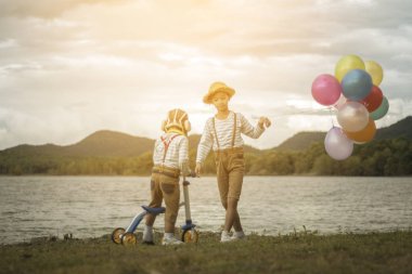 Balonlar ve renkli balonlarla kumsalda oynarken Bisiklet ile Asya kardeşler.