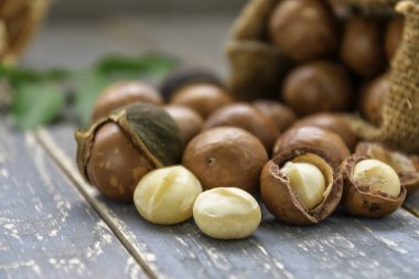 Macadamia fıstığı çuval ahşap zemin üzerine saçılan.