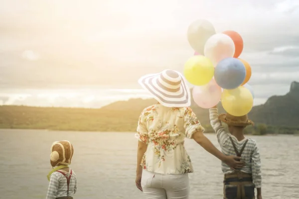Happy family holding colorful balloons outdoor on the beach having great holidays time on summer. Lifestyle, vacation, happiness, joy concept