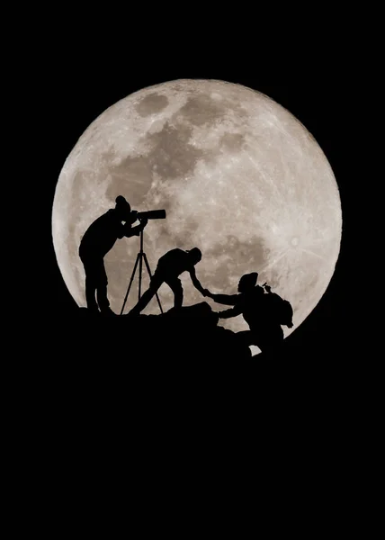 friends helping each other and with teamwork trying to reach top of mountains during super moon background