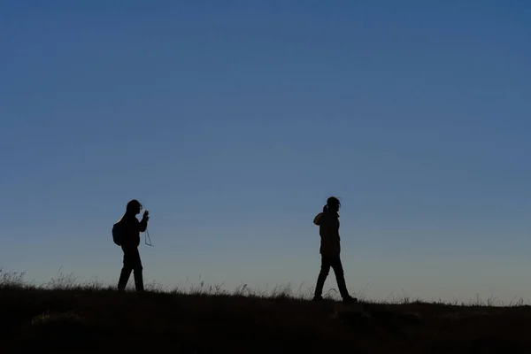 Silhouettes de randonneurs avec sacs à dos bénéficiant d'une vue coucher de soleil de t — Photo