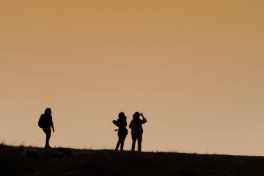 Sırt çantaları ile yürüyüşçüsiluetleri t gün batımı manzarasının keyfini çıkarın
