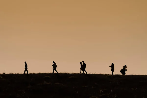 Силуэты туристов с рюкзаками, наслаждающихся видом на закат с высоты — стоковое фото