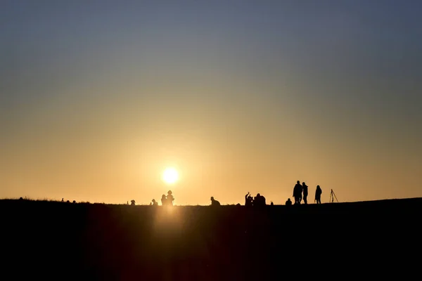 Silhuetas de caminhantes com mochilas desfrutando de vista do pôr do sol a partir de t — Fotografia de Stock