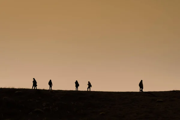 Silhuetter av vandrare med ryggsäckar njuter solnedgång utsikt från t — Stockfoto