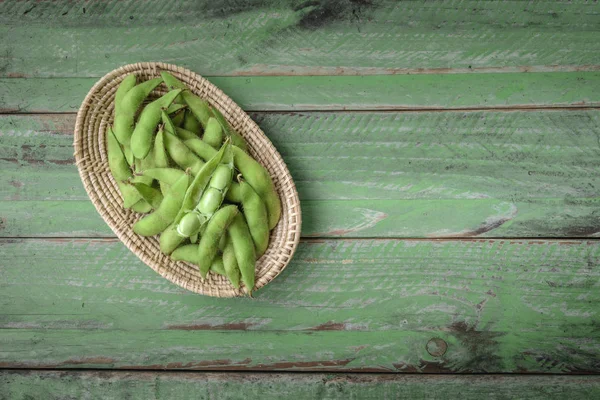 Groene Japanse sojabonen in houten kom op tafel hout — Stockfoto