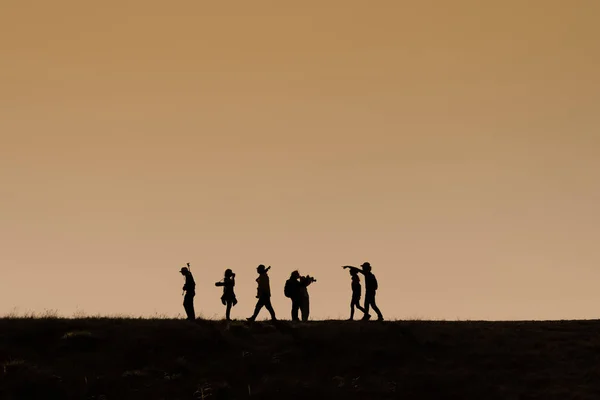 Silhuetter av vandrare med ryggsäckar njuter solnedgång utsikt från t — Stockfoto