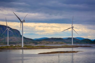 Norveç 'in Bjugn bölgesinde gün batımında Norveç kıyı şeridi boyunca duran rüzgar jeneratörleri 