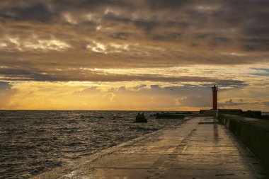 Rigas Körfezi 'nde Mangalsala hafif eviyle renkli fırtınalı gün batımı 